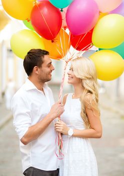 summer holidays, celebration and dating concept - couple with colorful balloons in the city