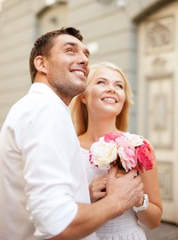 summer holidays and dating concept - couple with bouquet of flowers in the city