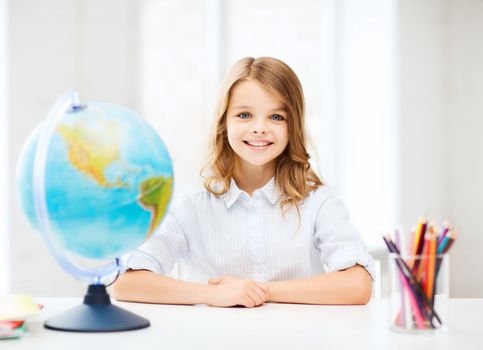 education and school concept - little student girl with globe at school