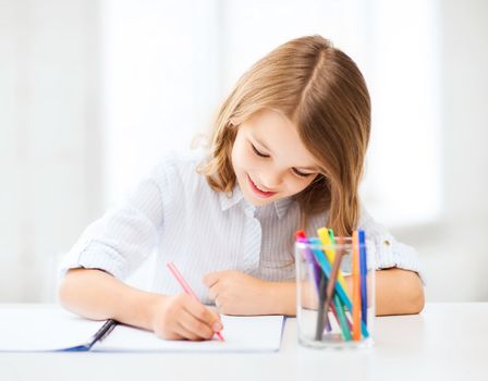 education and school concept - little student girl drawing at school