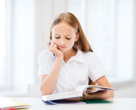 education and school concept - little student girl studying at school