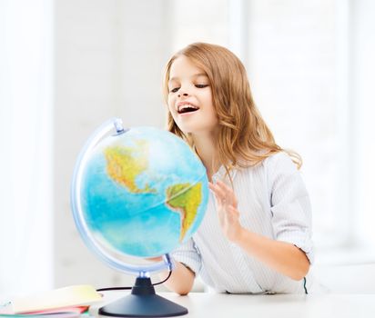 education and school concept - little student girl with globe at school