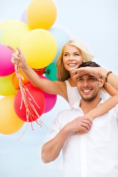 summer holidays, celebration and dating concept - couple with colorful balloons at seaside