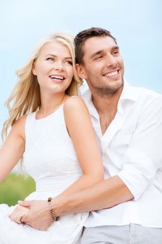 summer holidays and dating concept - couple in shades sitting at sea side