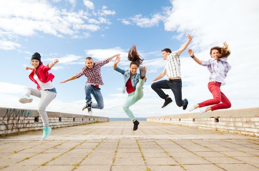 summer, sport, dancing and teenage lifestyle concept - group of teenagers jumping