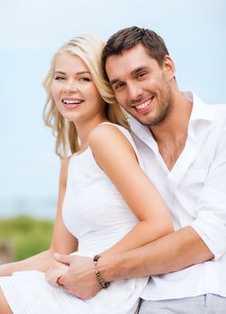 summer holidays and dating concept - couple in shades sitting at sea side