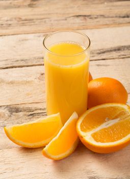 fruits and juice concept - glass of orange juice with oranges on the wooden table