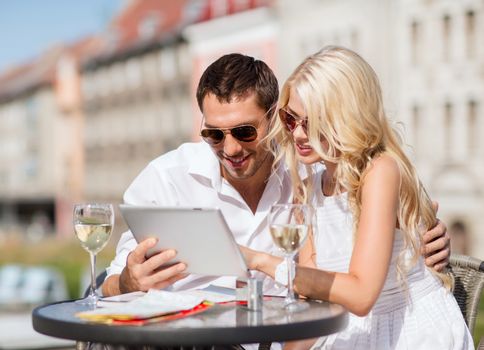 summer holidays, dating and technology concept - couple looking at tablet pc in cafe in the city