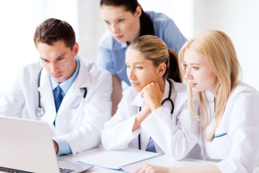 healthcare, medical and technology concept - group of doctors looking at laptop