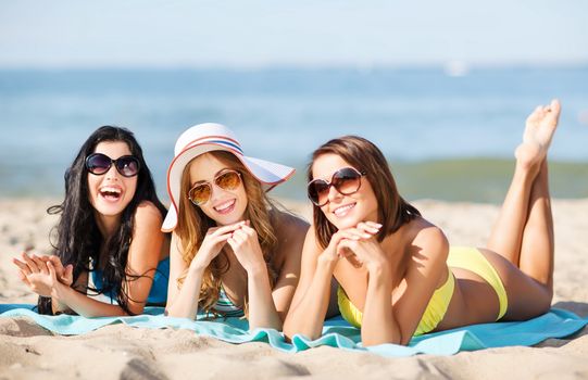 summer holidays and vacation - girls in bikinis sunbathing on the beach