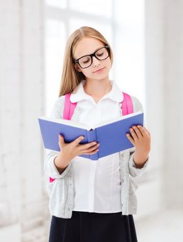 education and school concept - little student girl reading book at school