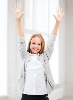 education and school concept - little student girl with hands up at school