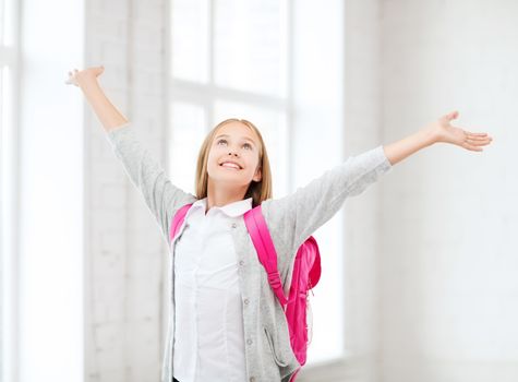 education and school concept - little student girl with hands up at school