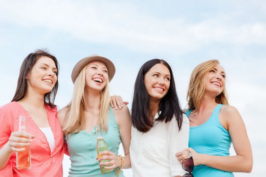 summer holidays and vacation concept - girls with drinks on the beach