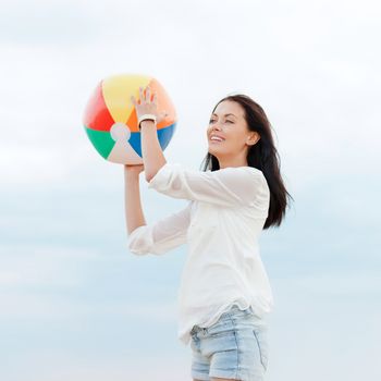 summer holidays, vacation and beach activities concept - girl with ball on the beach