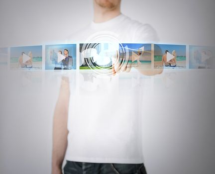 technology, internet, tv and virtual screens concept - man pressing button on virtual screen with videos