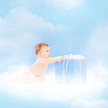 childhood and present concept - smiling baby sitting on the cloud with big gift box