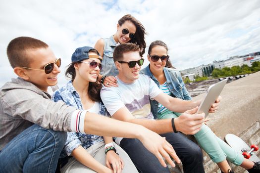 summer holidays, teenage and technology concept - group of teenagers looking at tablet pc