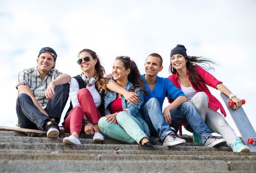 summer holidays and teenage concept - group of teenagers with skates outside