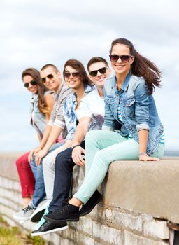 summer holidays and teenage concept - group of teenagers hanging out outside