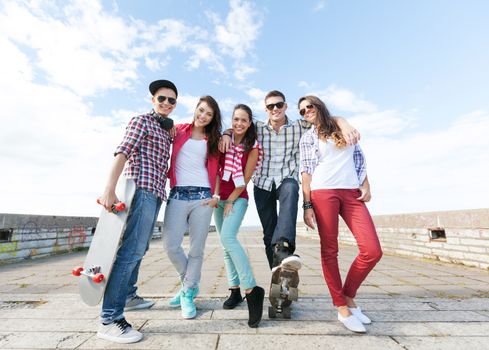 summer holidays and teenage concept - group of teenagers with skates outside