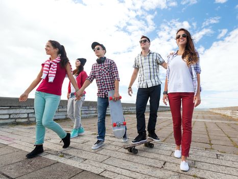 summer holidays and teenage concept - group of teenagers with skates outside