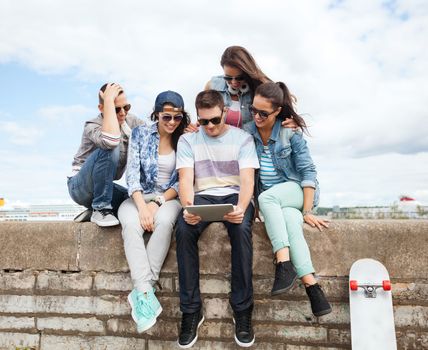 summer holidays, teenage and technology concept - group of teenagers looking at tablet pc