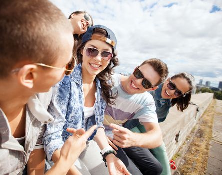 summer holidays and teenage concept - group of teenagers hanging out outside