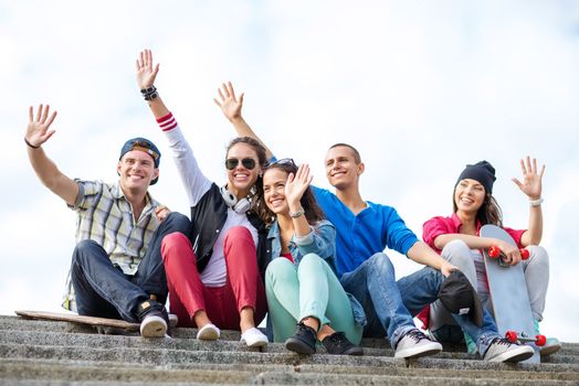 summer holidays and teenage concept - group of teenagers waving hands outside