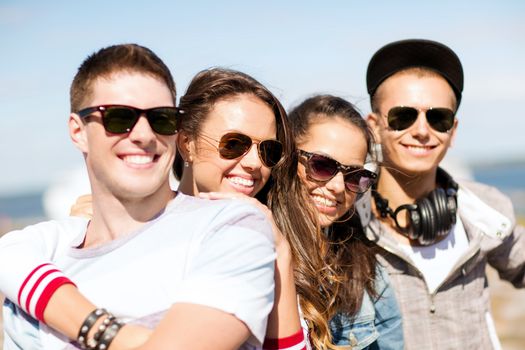 summer holidays and teenage concept - group of teenagers hanging out outside