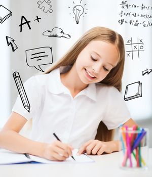 education and school concept - little student girl drawing at school