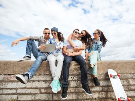 summer holidays, teenage and technology concept - group of teenagers looking at tablet pc