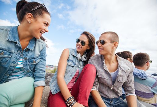 summer holidays and teenage concept - group of teenagers hanging out outside