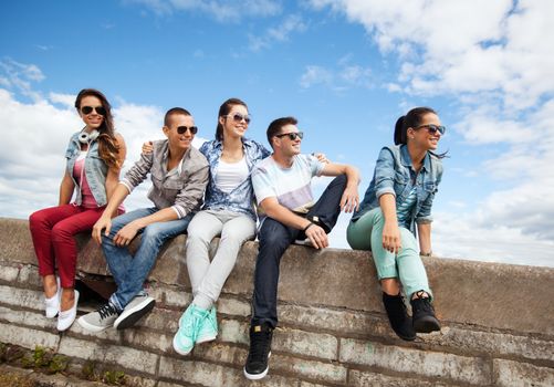 summer holidays and teenage concept - group of teenagers hanging out outside