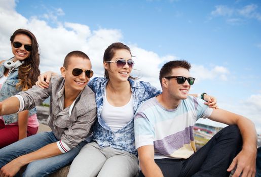 summer holidays and teenage concept - group of teenagers hanging out outside