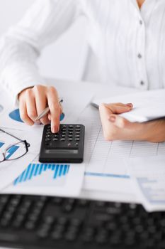 business, office, school and education concept - woman hand with calculator and papers