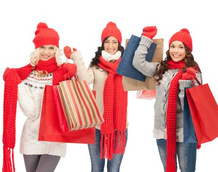 shopping and christmas concept - girls in red scarfs and hats with shopping bags
