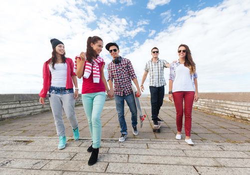 summer holidays and teenage concept - group of teenagers with skates outside