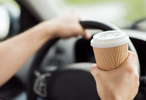 transportation and vehicle concept - man drinking coffee while driving the car