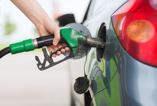 transportation and ownership concept - man pumping gasoline fuel in car at gas station