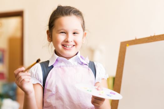 Portrait of Asian girl in apron interested in painting at an art school