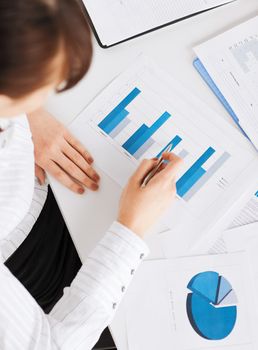 business, office, school and education concept - woman hand with charts and papers
