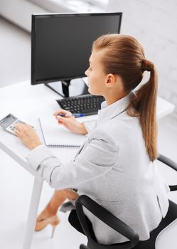 business, office, school and education concept - businesswoman with notebook and calculator