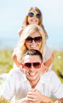 summer holidays, children and people concept - happy family with blue sky and green grass