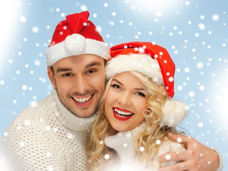 christmas, x-mas, winter, happiness concept - family couple in sweaters and santa's hats