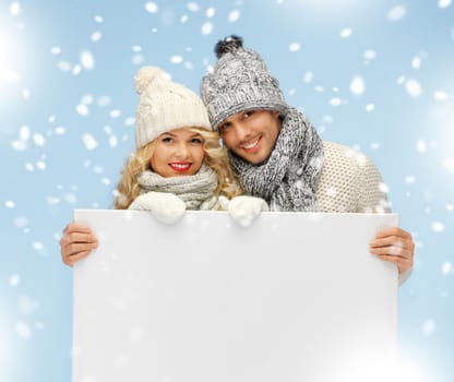 christmas, x-mas, winter, happiness concept - family couple in a winter clothes holding blank board