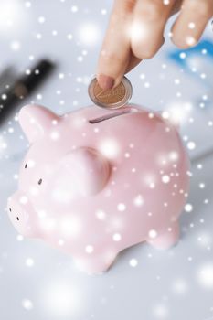 picture of woman hand putting coin into small piggy bank