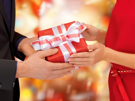 christmas, x-mas, winter, holidays, happiness concept - man and woman hands with gift box