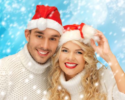 christmas, x-mas, winter, happiness concept - family couple in sweaters and santa's hats