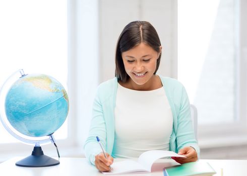 education and school, travel concept - female teacher with globe and notepad